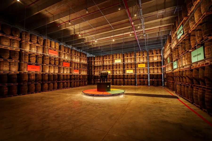 BACARDÍ aging warehouse in Puerto Rico: rum barrels on tall racks with coloured flavour signs and a round platform with a barrel